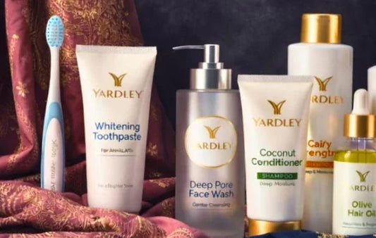 Yardley skincare & haircare products including toothpaste, face wash, conditioner, and hair oil on fabric backdrop