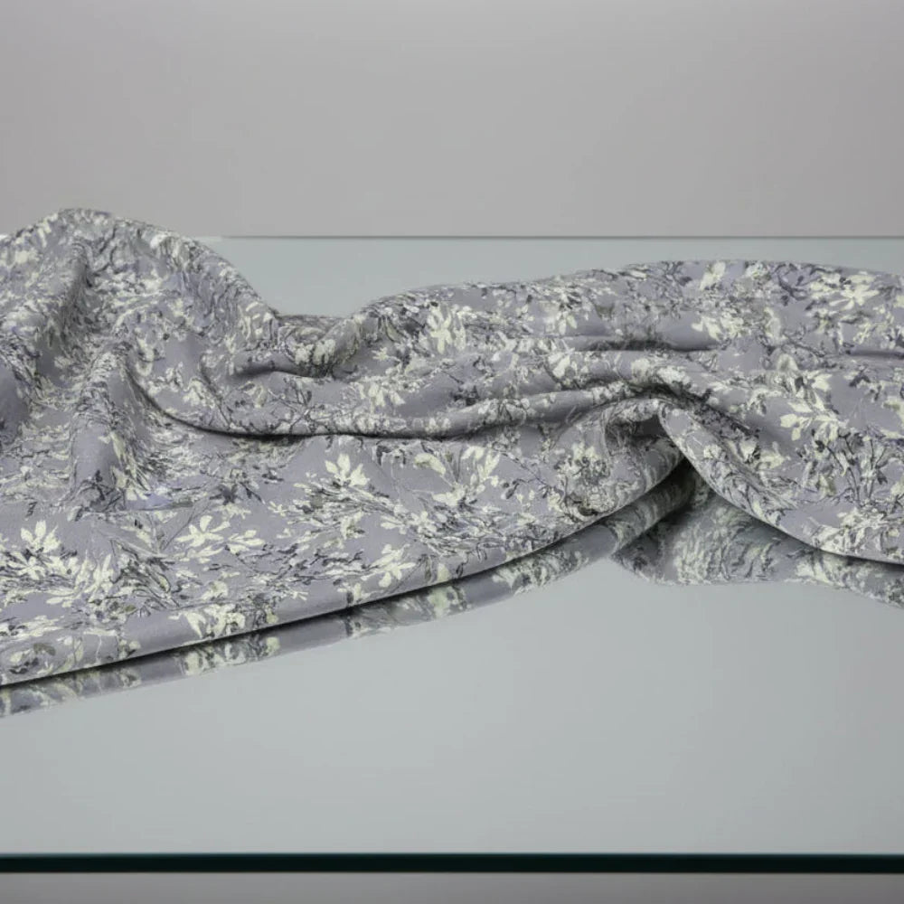 Gray floral print fabric draped on glass surface, soft texture, elegant design